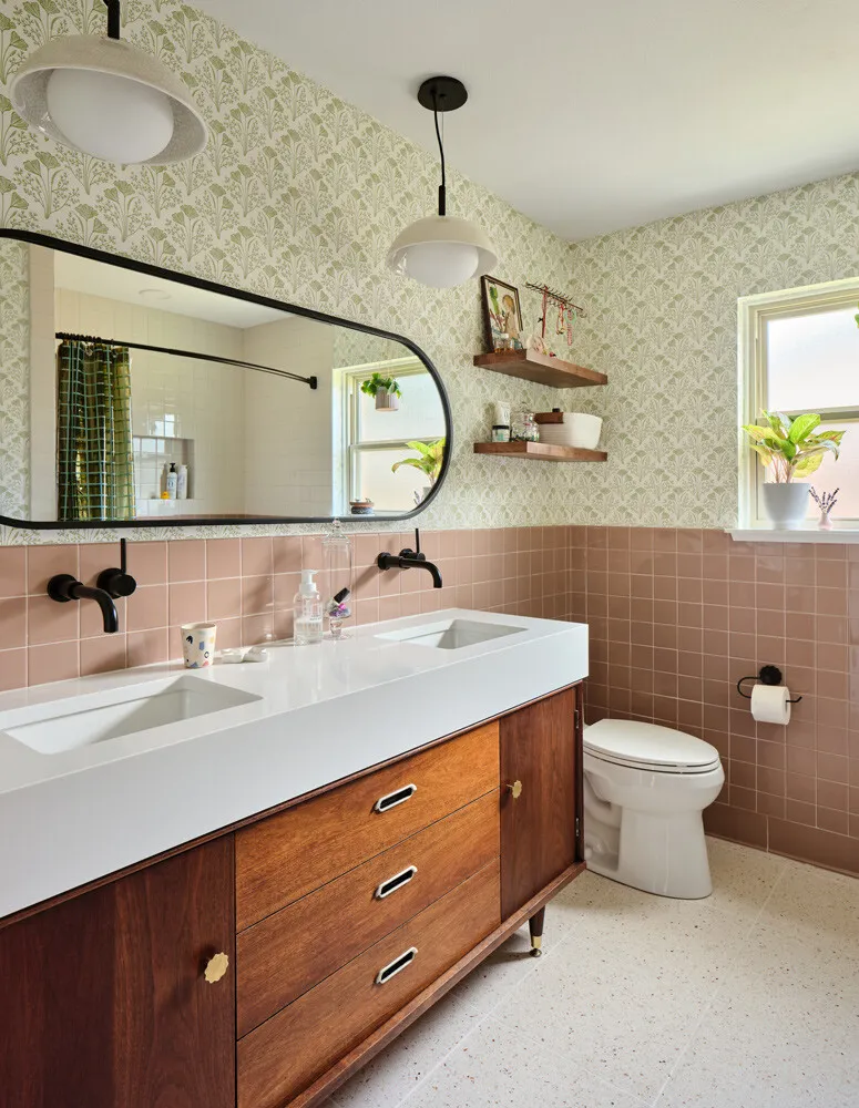 Bathroom with pink tile wainscoting, a walnut vanity and a long black-framed mirror
