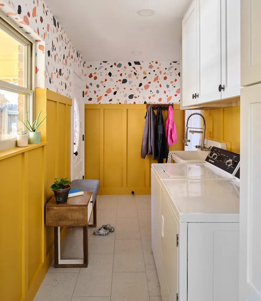 Laundry room with mustard wainscoting, terrazzo wallpaper and white cabinets