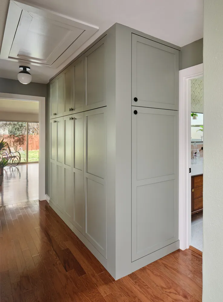 Sage green built-in cabinets along a hallway