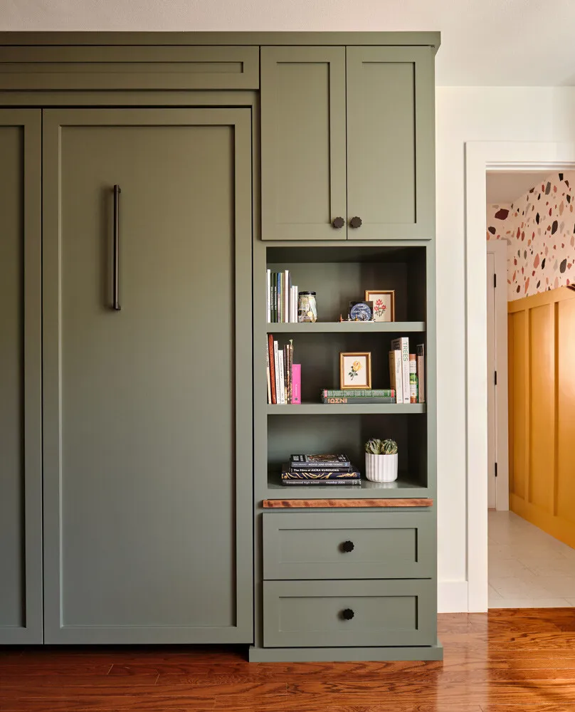 Sage green Murphy bed cabinet beside open shelving