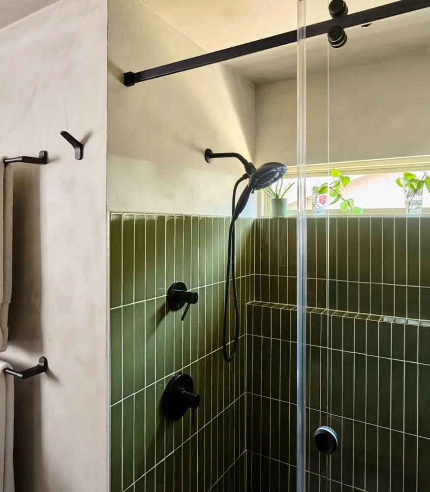 Shower with green vertical tile, black fixtures and a window