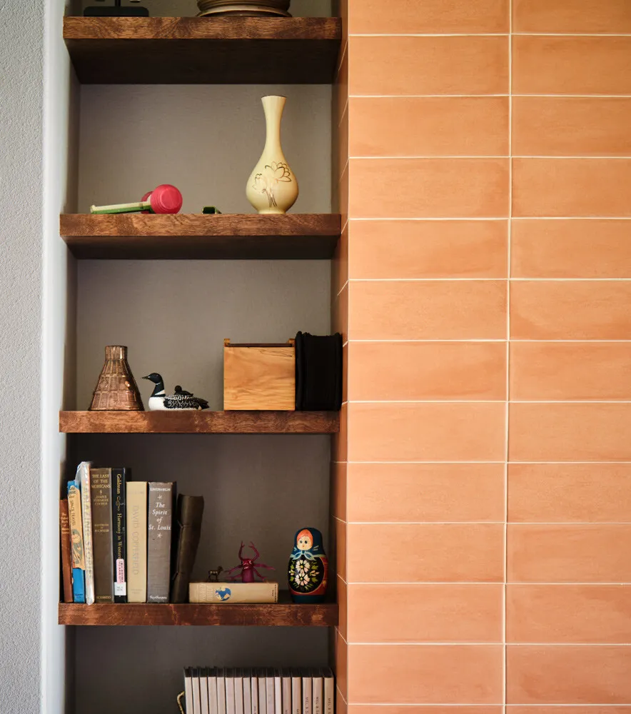 Wood niche shelves built into a coral tile fireplace wall
