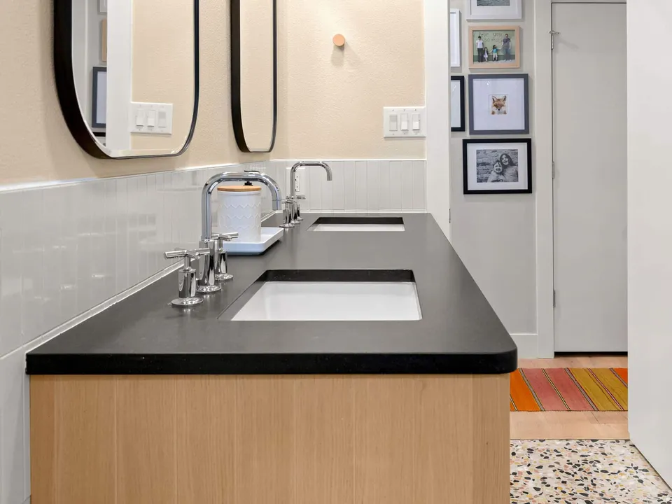 End of the black vanity counter with two sinks and a view to the hallway