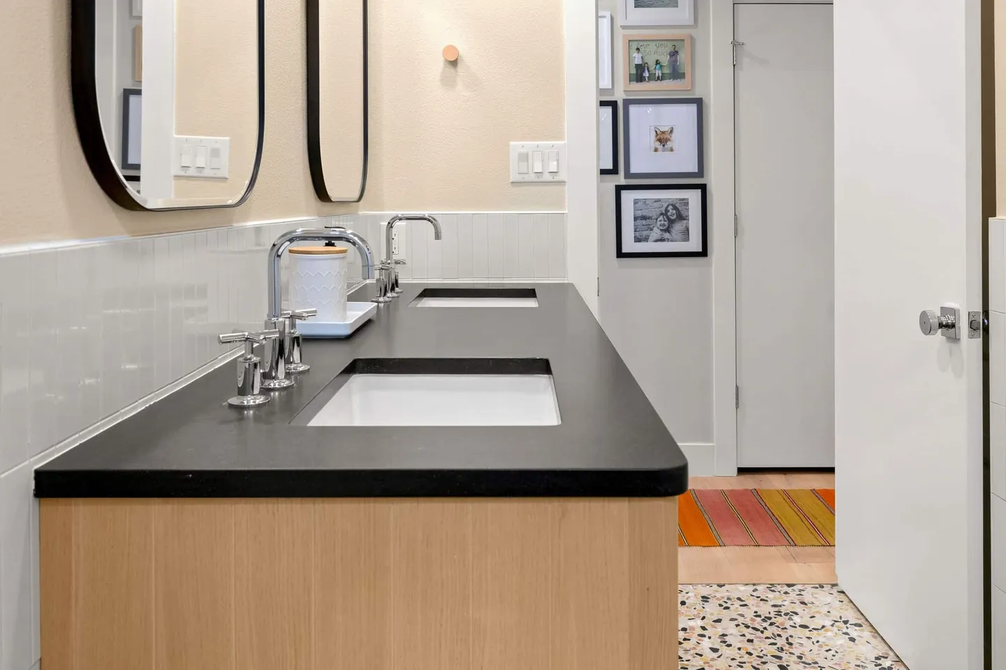End of the black vanity counter with two sinks and a view to the hallway