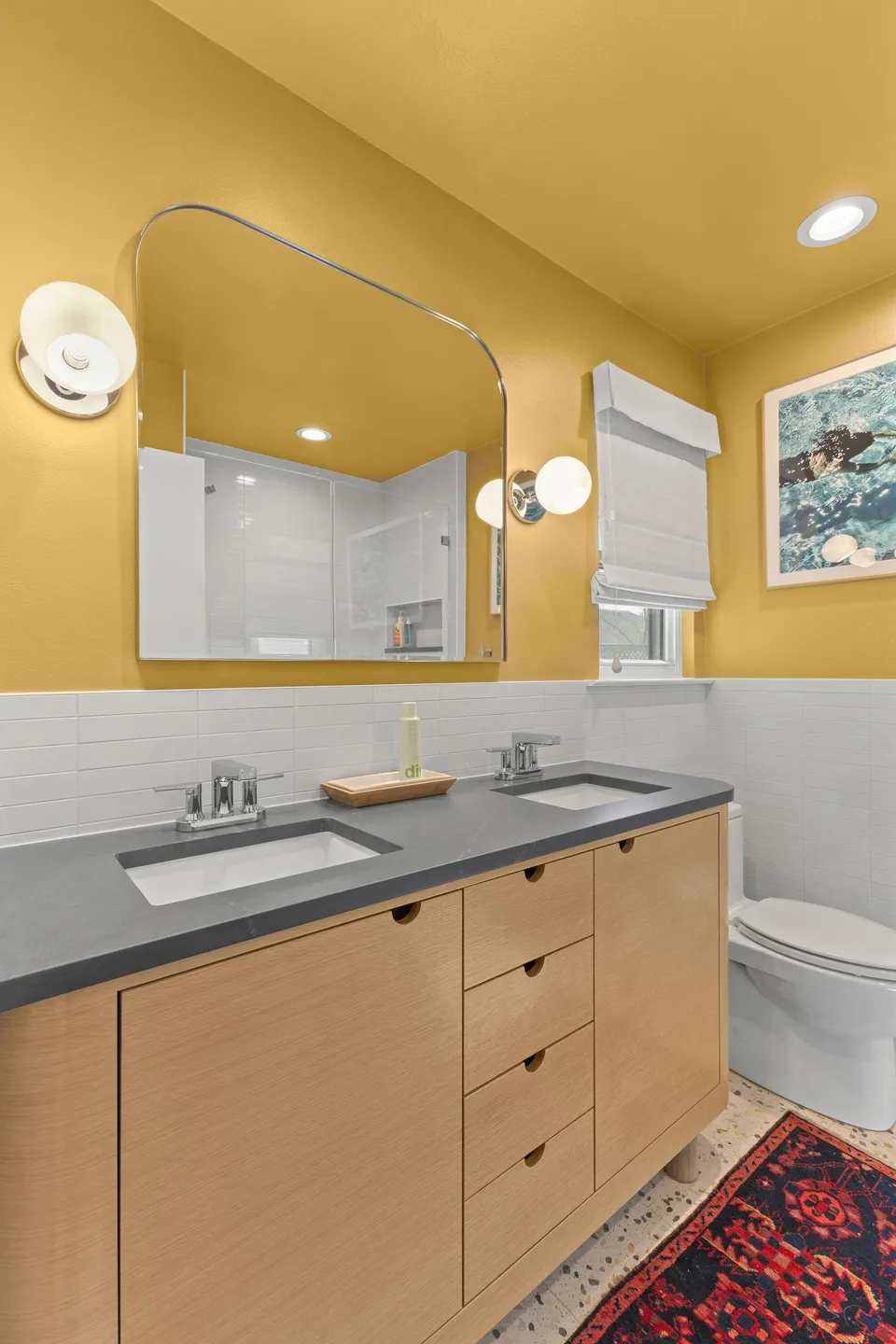 Primary bath with a yellow wall, an arched mirror and a white oak double vanity