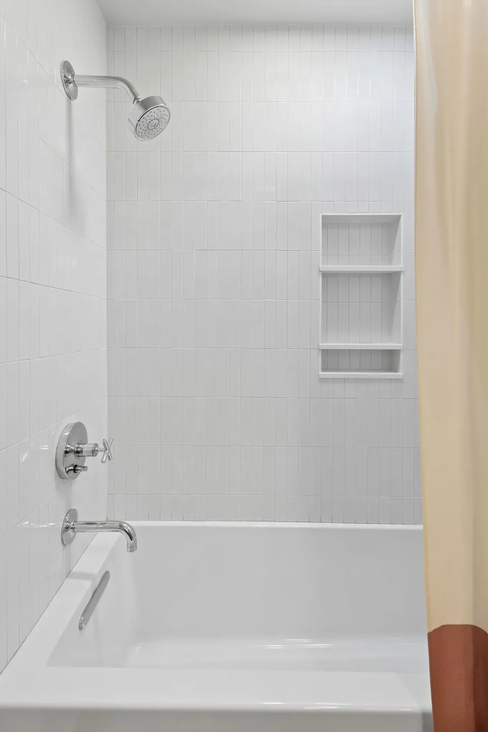 Tub and shower with white tile and a built-in niche