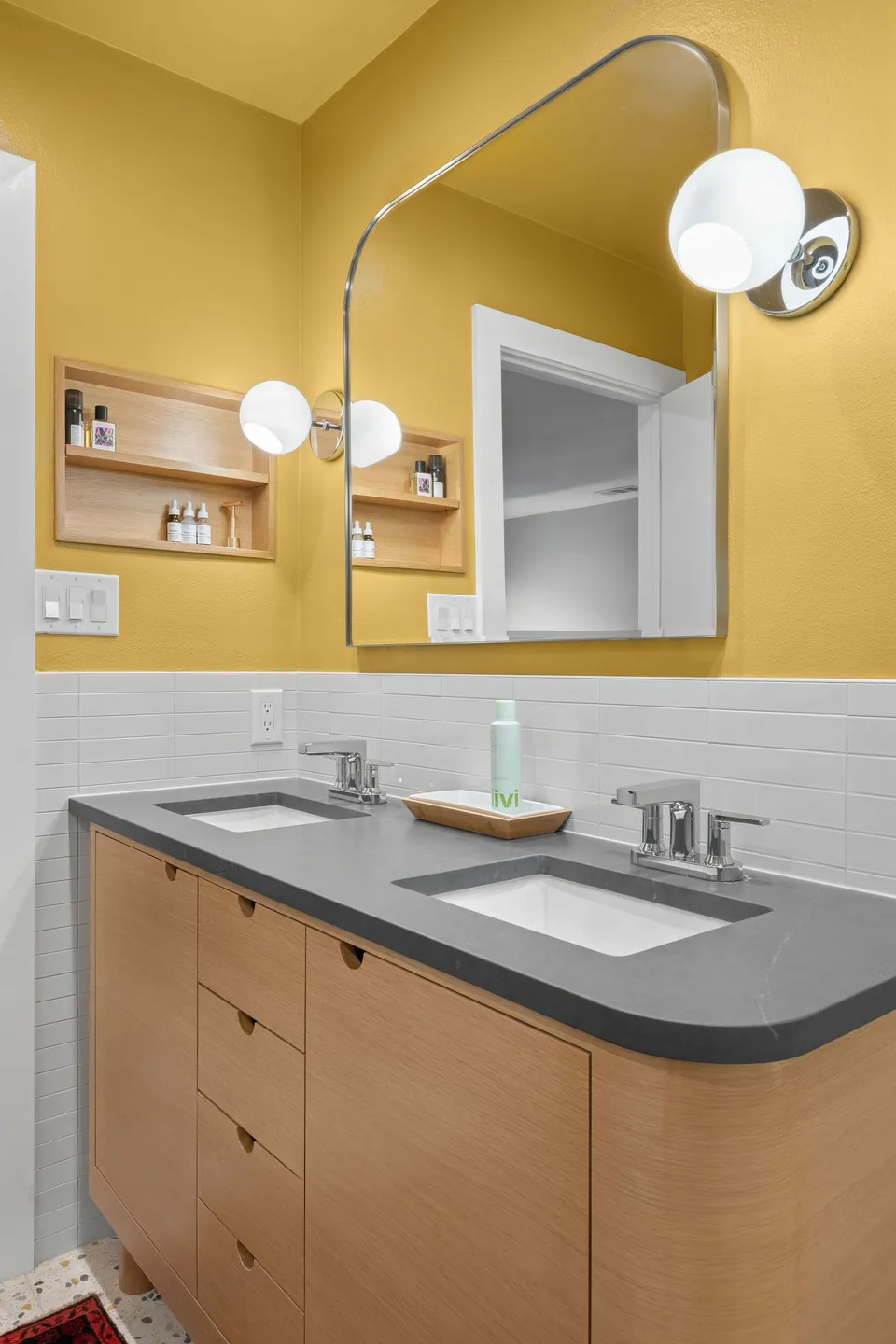White oak vanity with rounded corners, a grey counter and a mirror with shelves