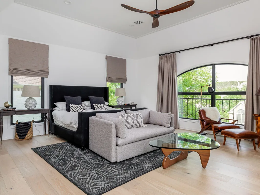 Bedroom with a sitting area, a glass coffee table, and a tall arched window