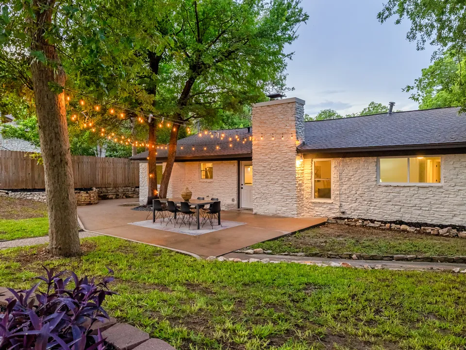 Back of the house with a patio, string lights and a stone chimney