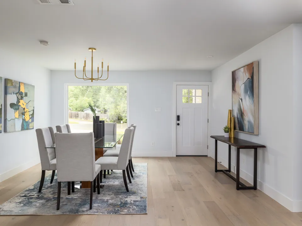 Dining room with a long table, a brass chandelier and a window to the backyard
