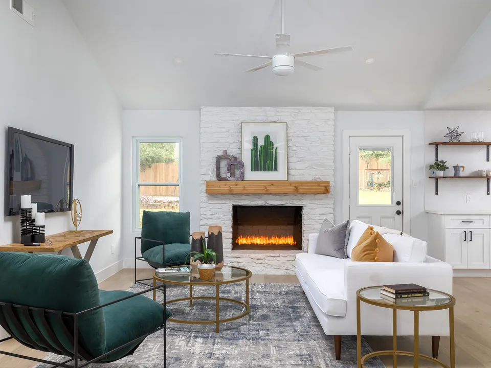 Living room with a TV beside a painted brick fireplace and green chairs