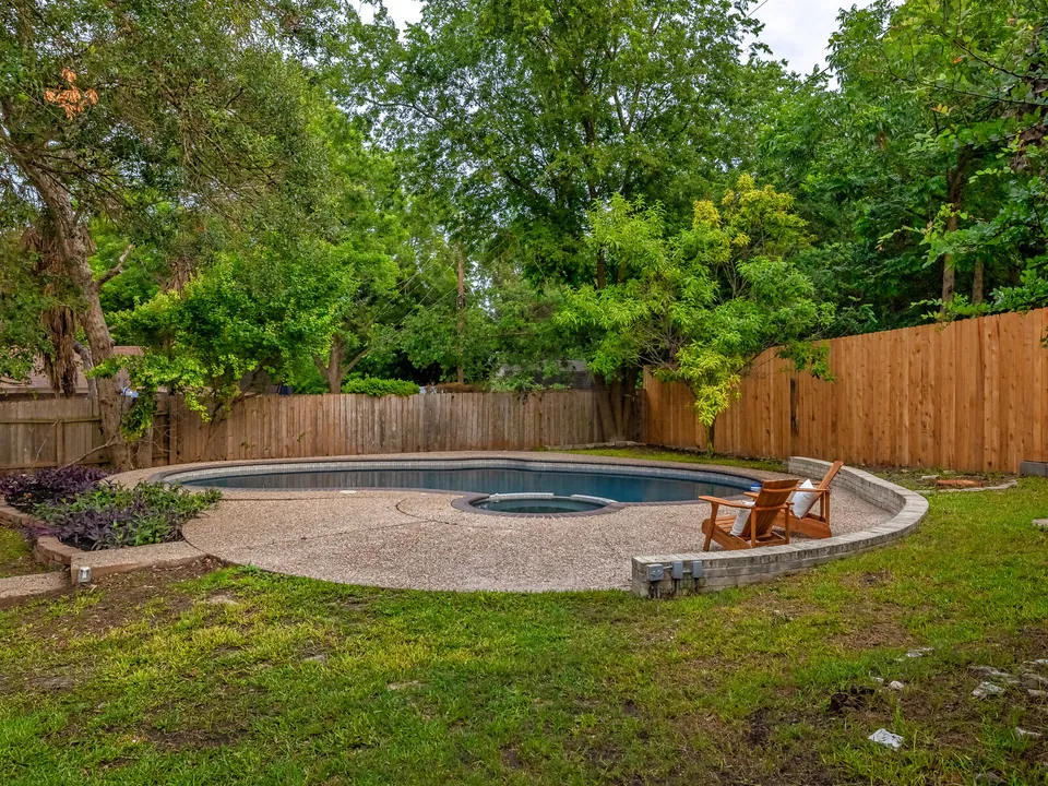 Pool deck with Adirondack chairs and a wood privacy fence