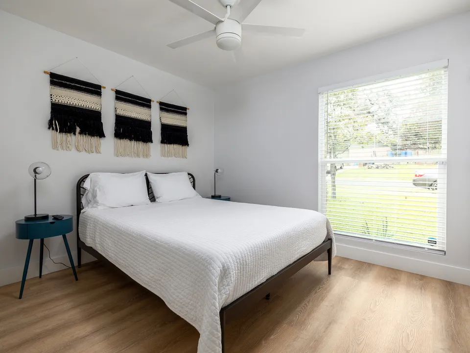 Bedroom with an iron bed, woven wall hangings and a teal side table