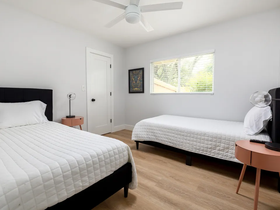 Bedroom with two beds, a black headboard and a coral side table