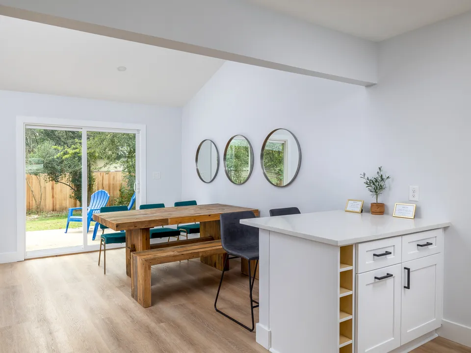 Dining area with a farmhouse table, round mirrors and a sliding door to the yard
