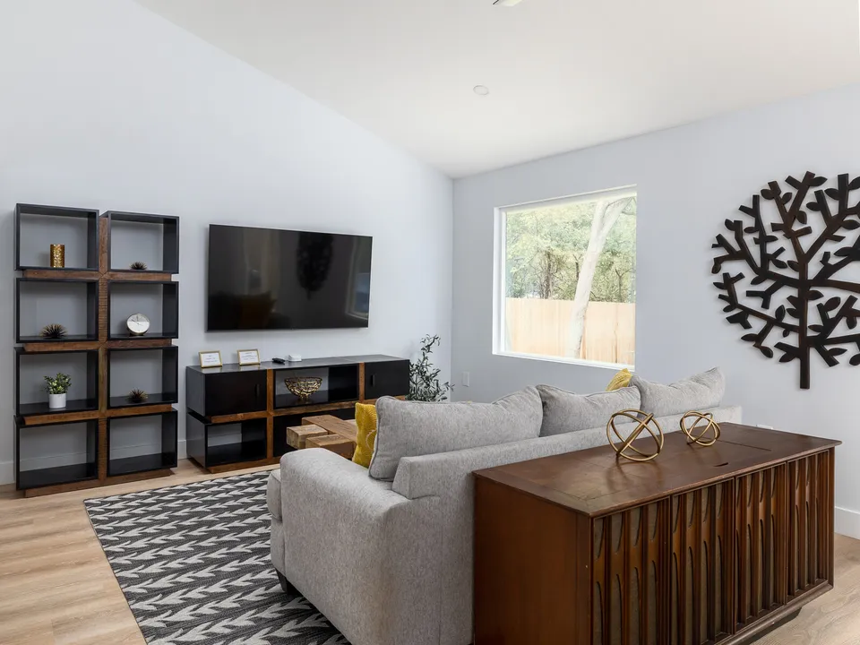 Living room with black shelving, a grey sofa and a metal tree wall sculpture