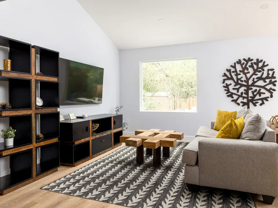 Living room with a vaulted ceiling, black shelving and a wood block coffee table
