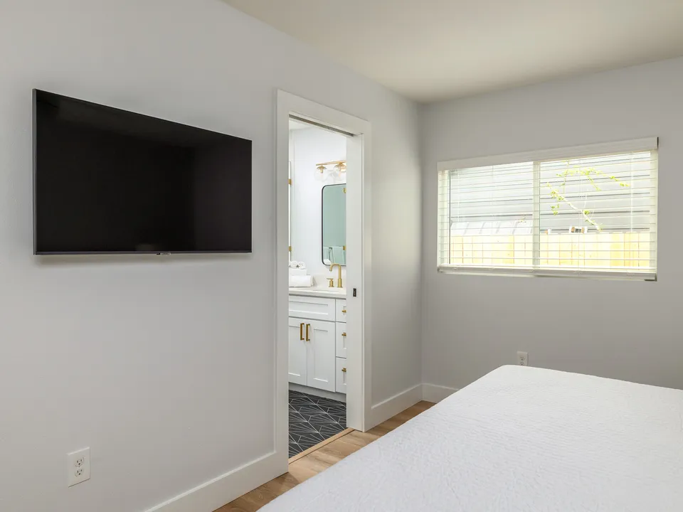 Room with a wall-mounted TV and a doorway to a bathroom
