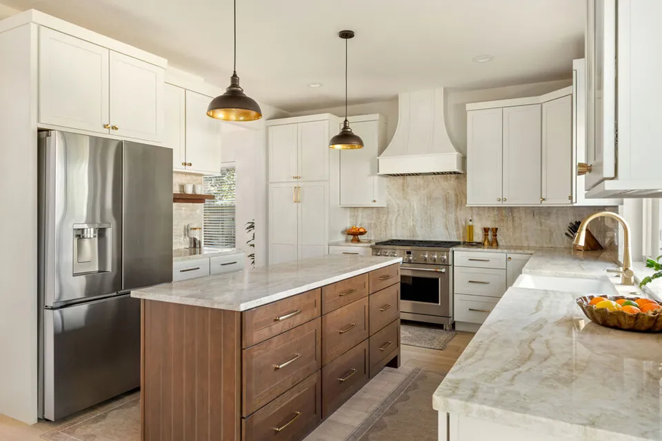 Kitchen with a walnut island, quartzite counters, black pendants and a stainless refrigerator
