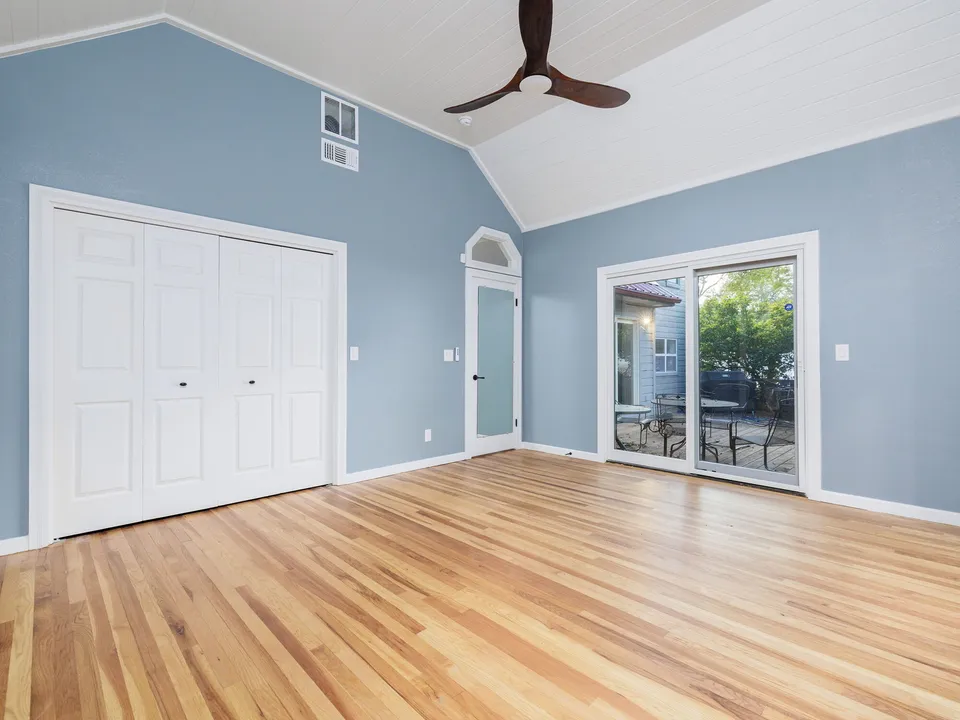 Bedroom with blue walls, a vaulted ceiling, a double closet and sliding doors to the yard