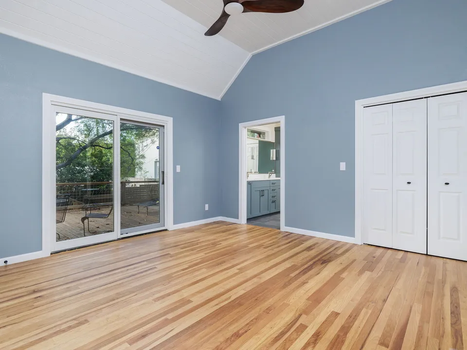 Blue bedroom with sliding glass doors, a closet and a doorway to the bathroom