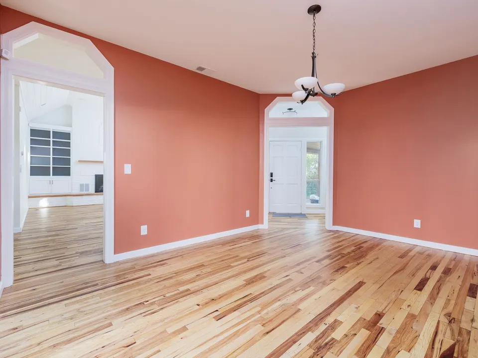 Coral dining room with arched doorways and restored oak floors