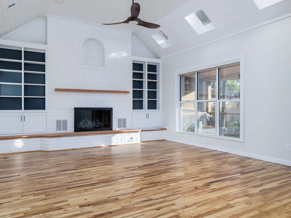 Living room with a white painted brick fireplace, navy built-in shelves and skylights