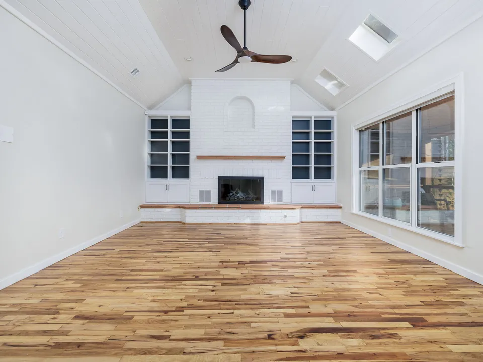 Vaulted living room with a white brick fireplace between navy bookshelves