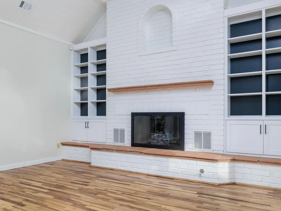 White painted brick fireplace with a wood mantel and navy built-in shelves