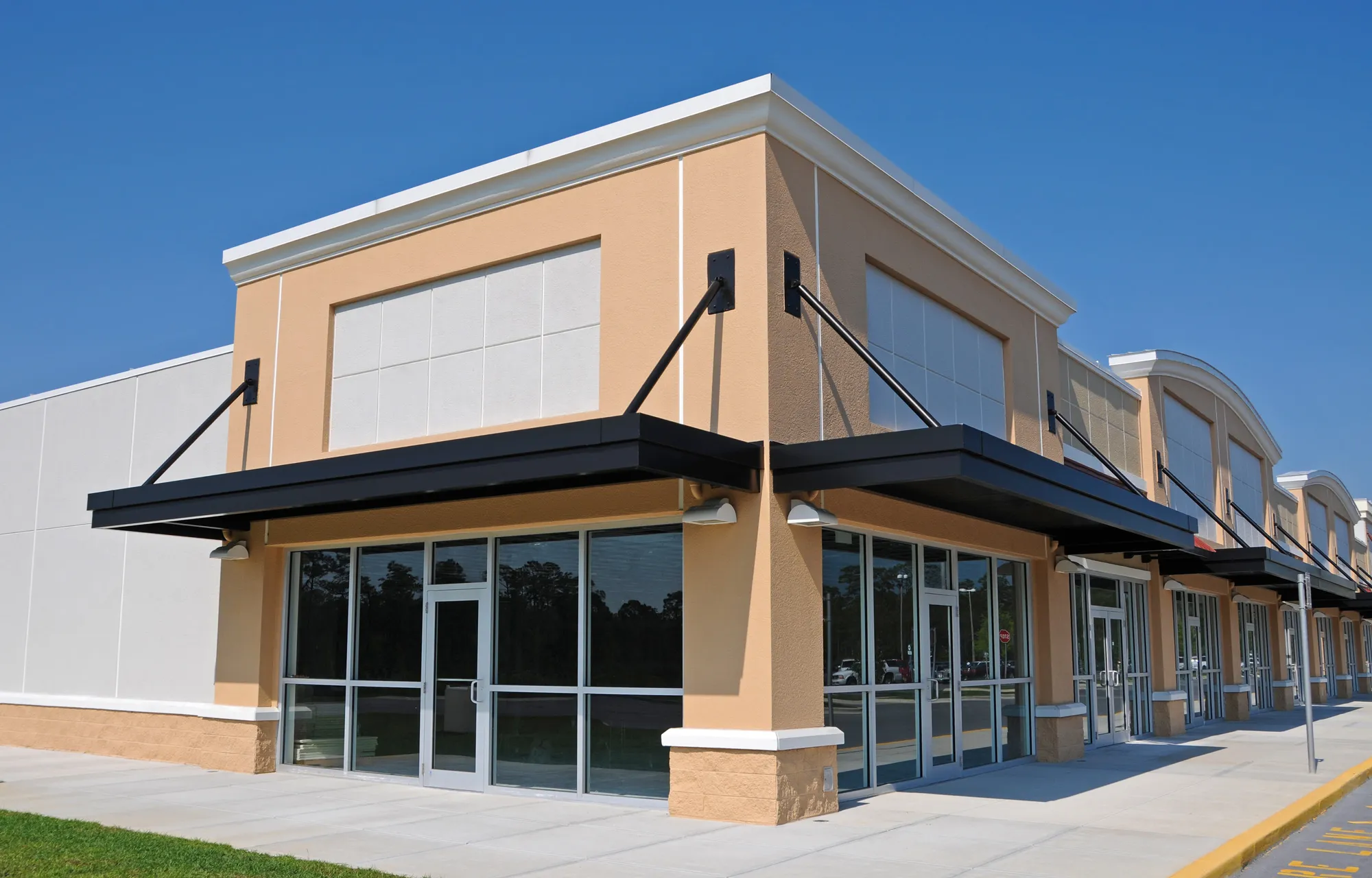 Row of retail storefronts with glass doors and black metal awnings