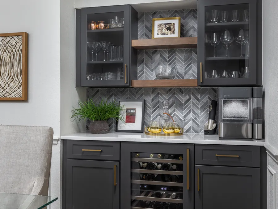 Built-in bar with charcoal glass-front cabinets, a wine fridge and grey herringbone tile