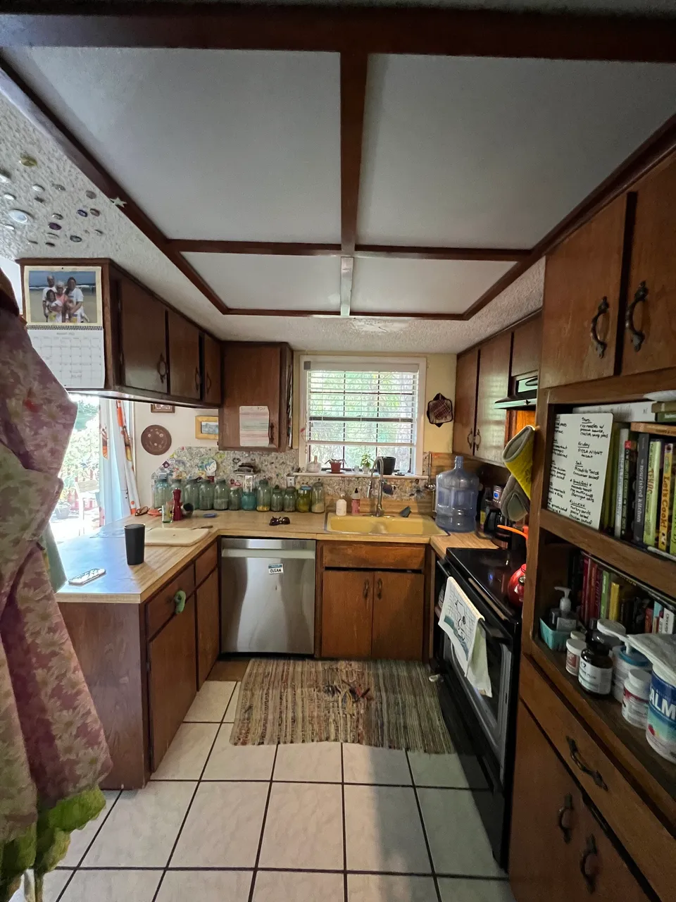 Galley kitchen before the remodel, with dark wood cabinets and a white tile floor