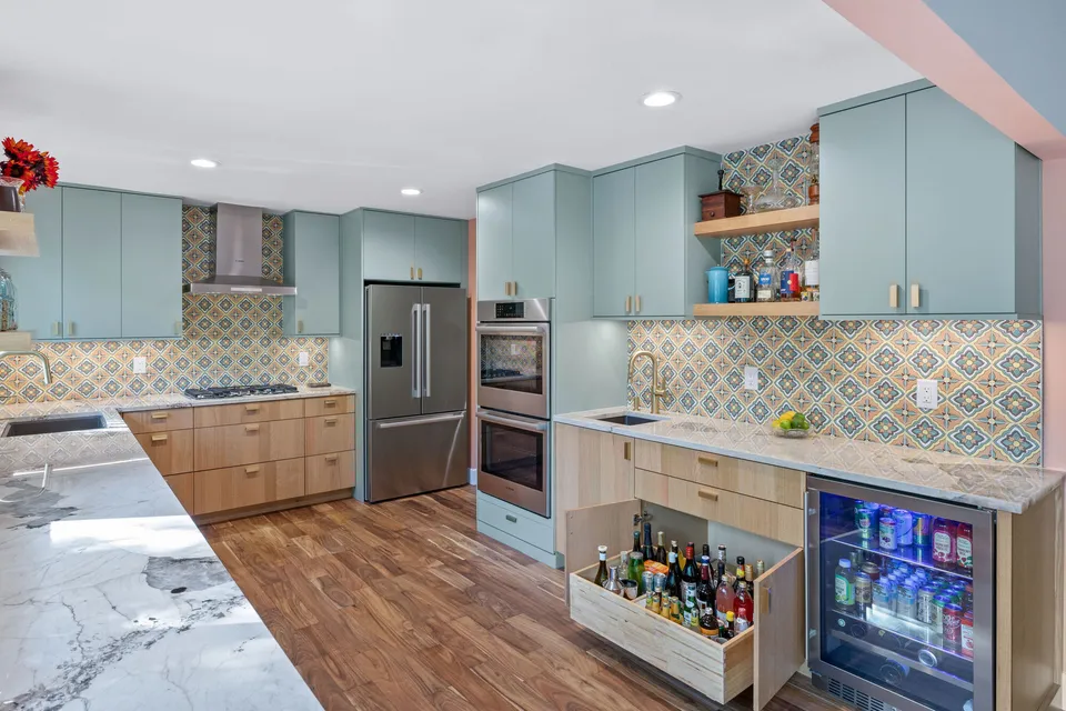 Kitchen with a pull-out drawer of bottles open beside a beverage fridge