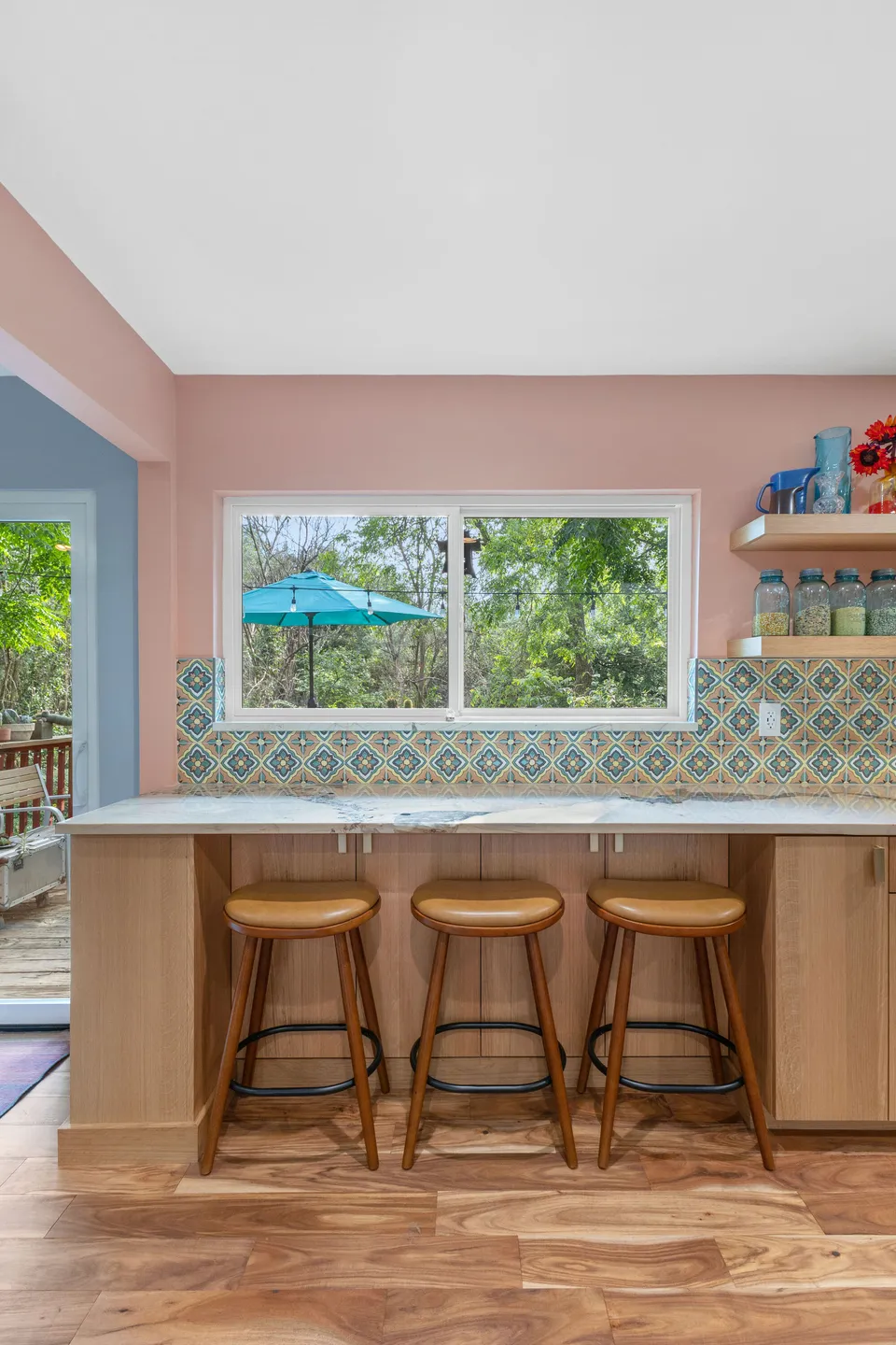 Peninsula with three wood bar stools under a window and patterned tile