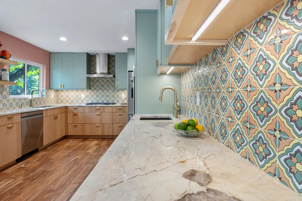 Quartzite counter along a patterned tile backsplash with a brass faucet