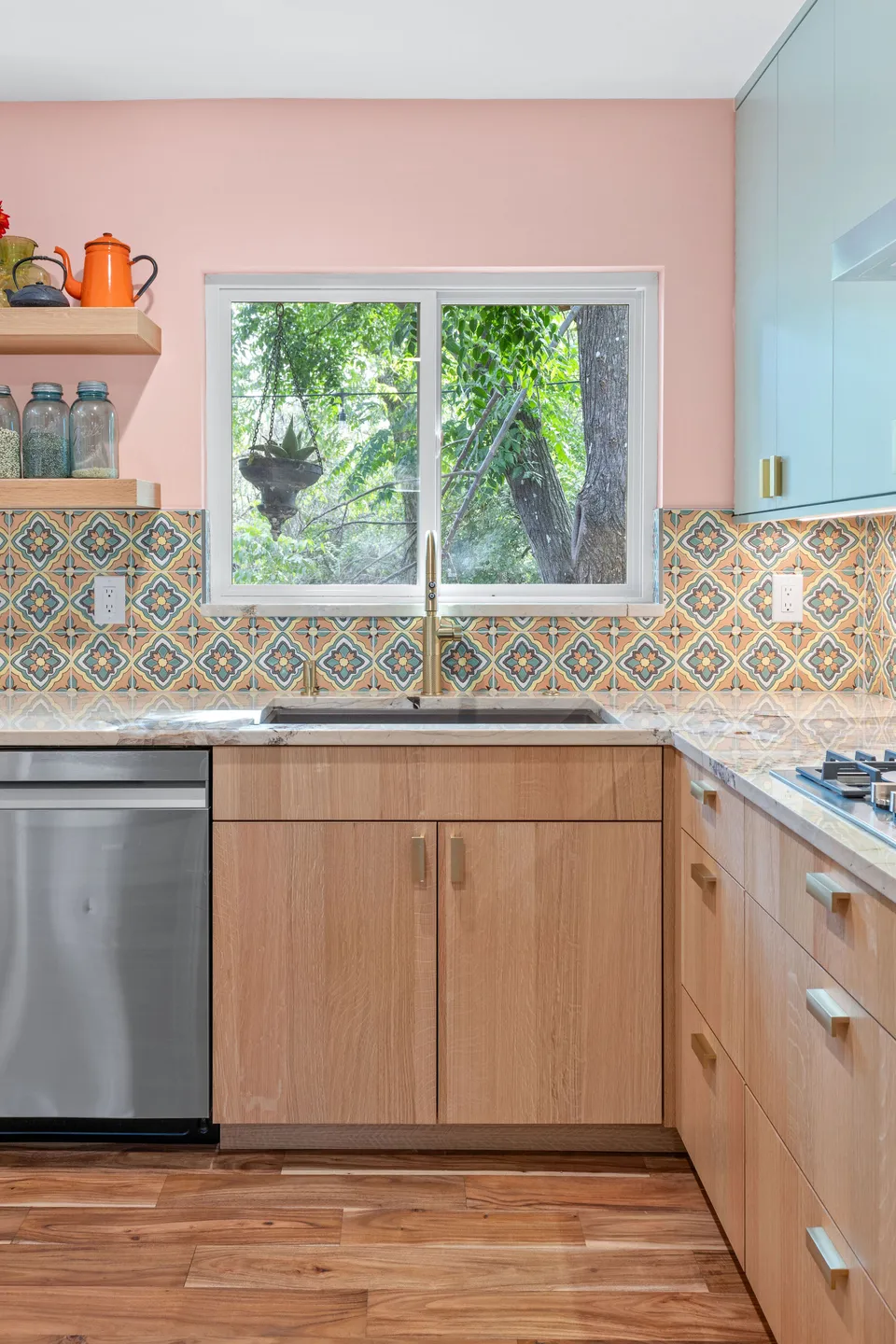 Sink below a window with white oak cabinets, a dishwasher and open shelves