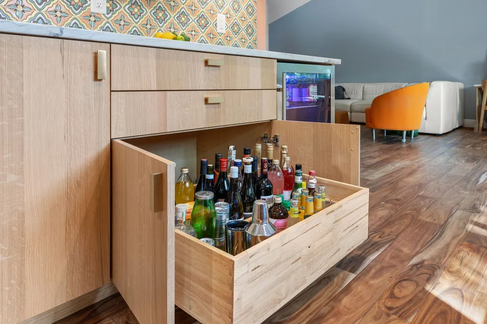 White oak pull-out drawer filled with liquor bottles