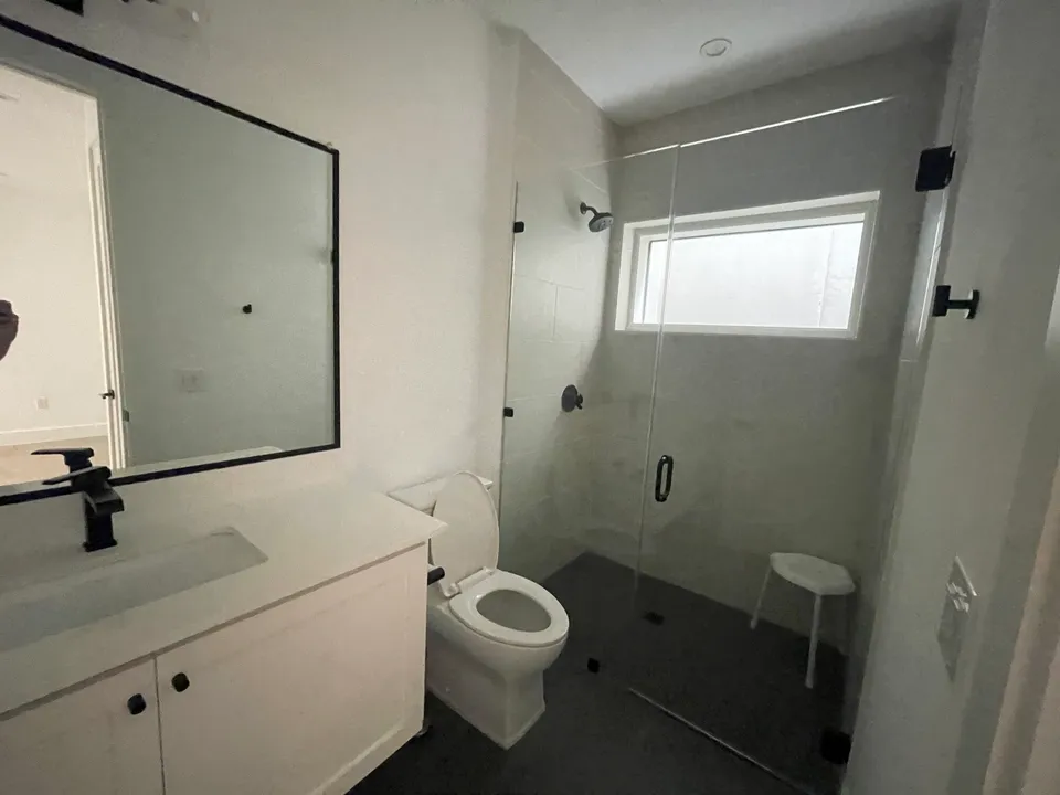 Bathroom before the remodel, with a plain white vanity and a glass shower