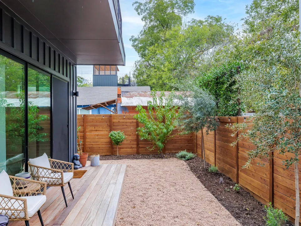 Covered wood deck with lounge chairs facing the gravel yard and cedar fence