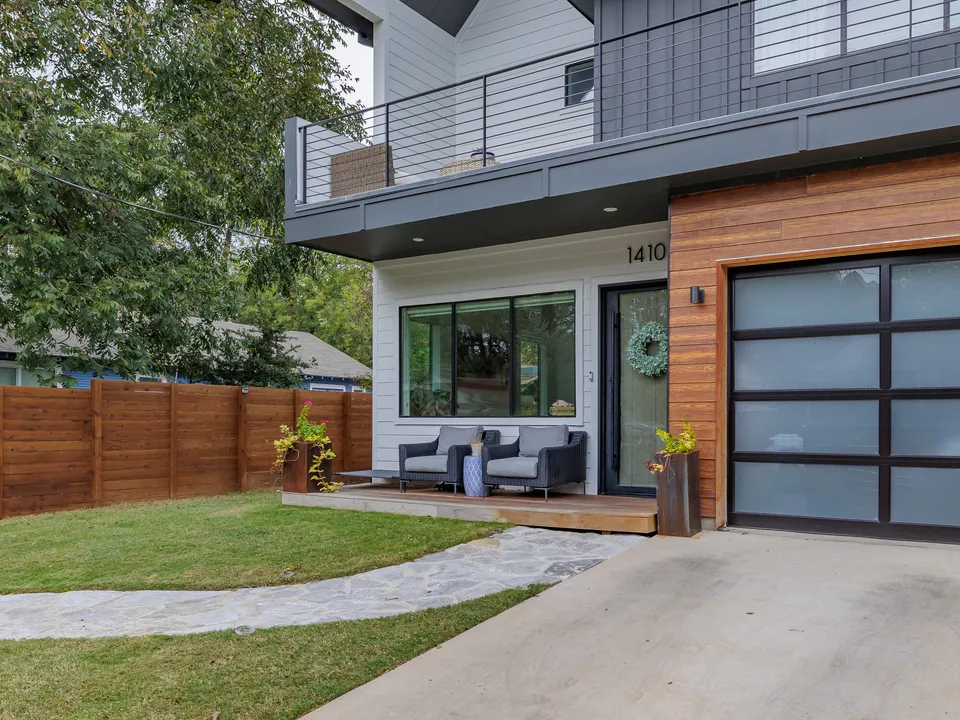Front porch with blue chairs beside a cedar-clad garage with a frosted glass door