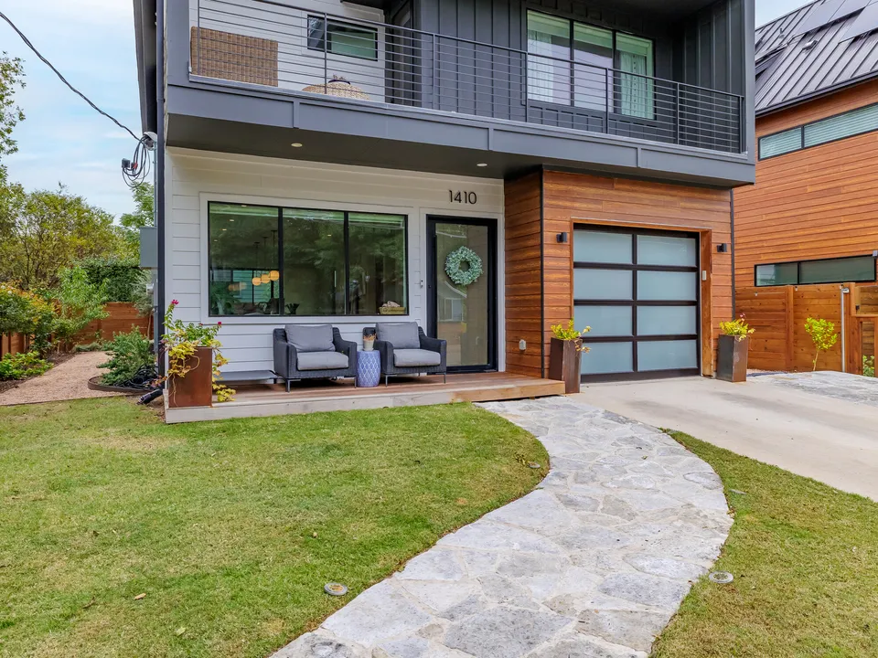 Front porch and glass garage door with a stone path through the lawn
