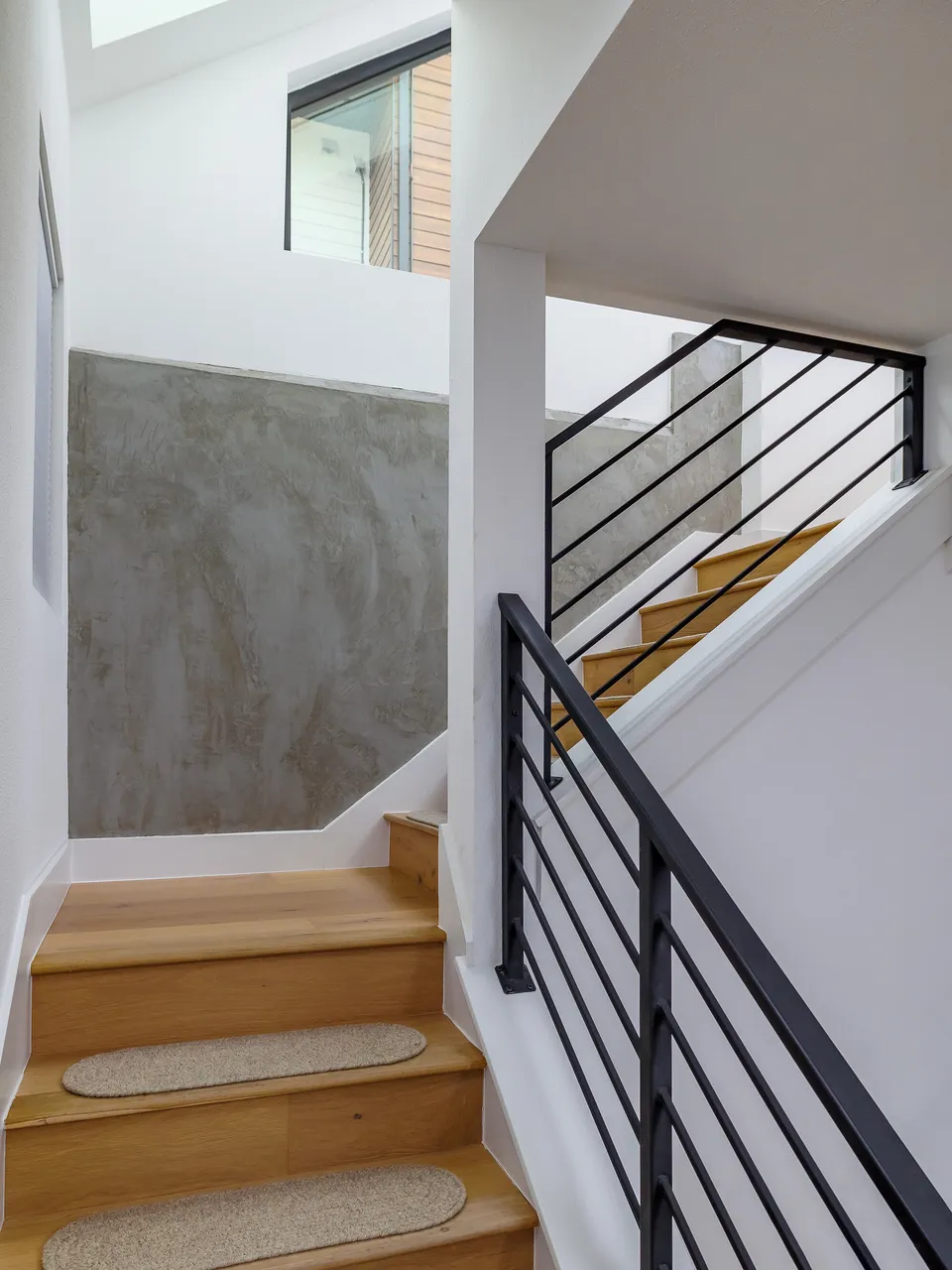 Interior stair with oak treads and a black metal railing up from the basement