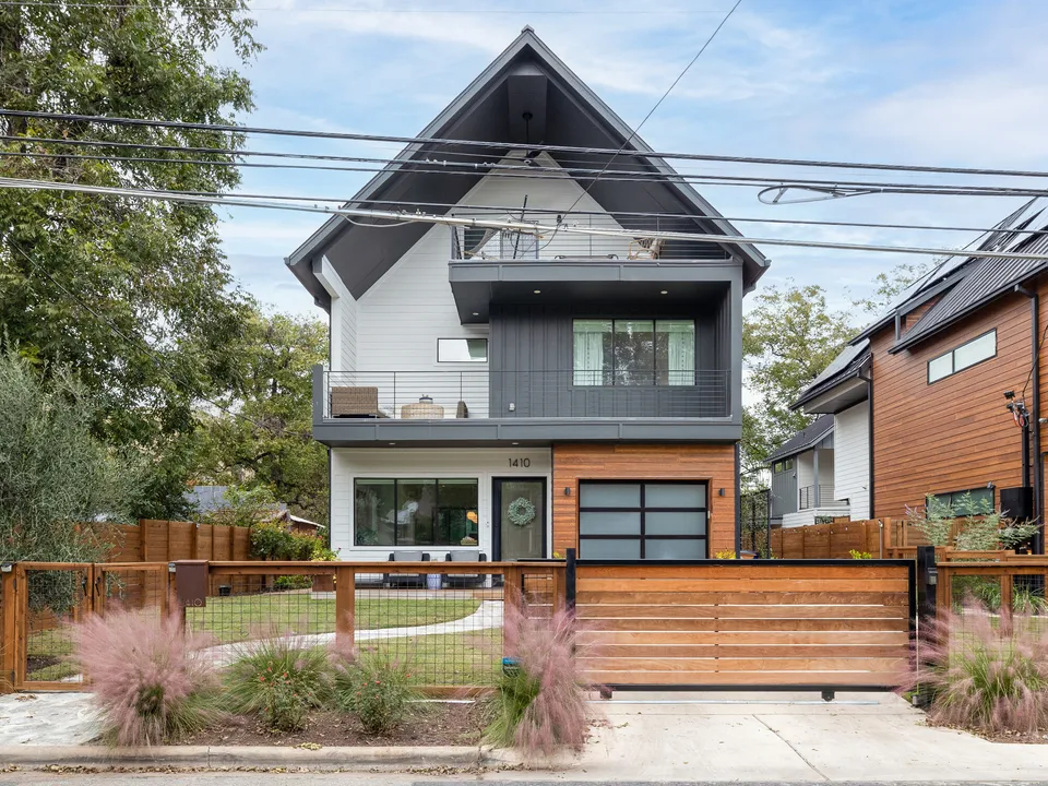 Modern house with a black gable, board and batten siding and a wood fence