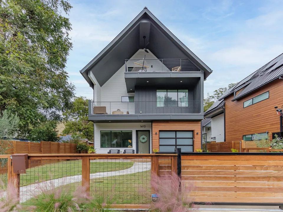 Modern house with a black gable roof, a balcony and a cedar-clad garage