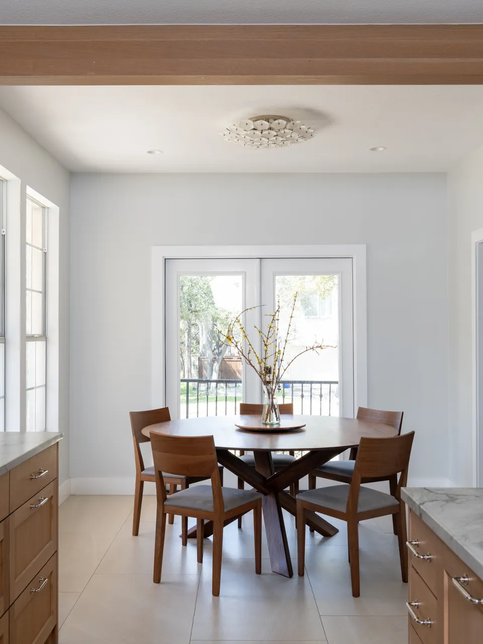 Dining nook with a round wood table in front of white French doors opening to a balcony