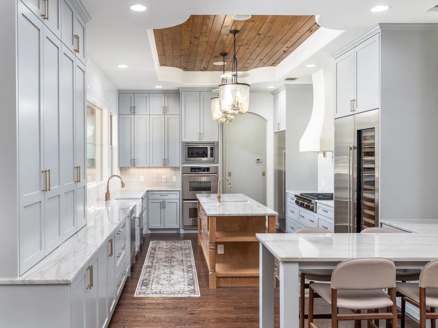 View along grey cabinets and the island under a wood plank ceiling