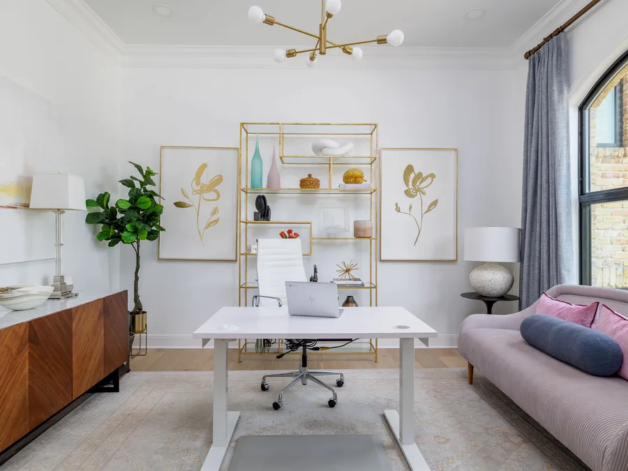 Home office with a white desk, brass shelving, and an arched window