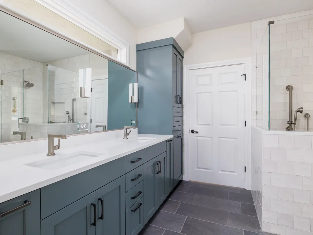 Bathroom with a teal double vanity, a long mirror, and a white tile walk-in shower