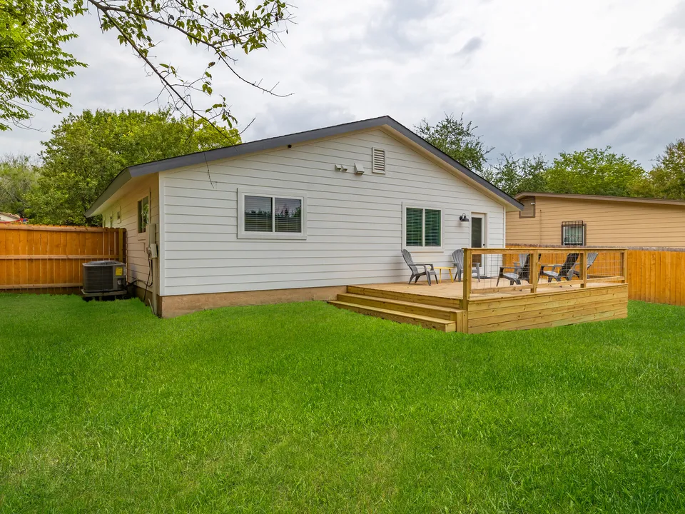 Back of the house with the addition, a deck and a cedar fence