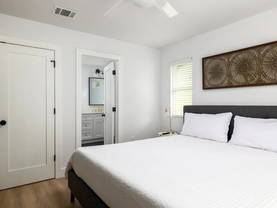 Bedroom with a grey bed, a carved wood wall panel and a doorway to the bath